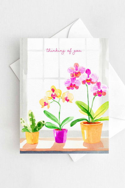 Thinking of You greeting card with watercolor orchids in pink and yellow, A2 size (5.5” x 4.25”), includes a white envelope.