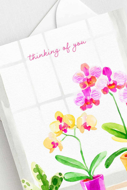 Thinking of You greeting card with watercolor orchids in pink and yellow, A2 size (5.5” x 4.25”), includes a white envelope.